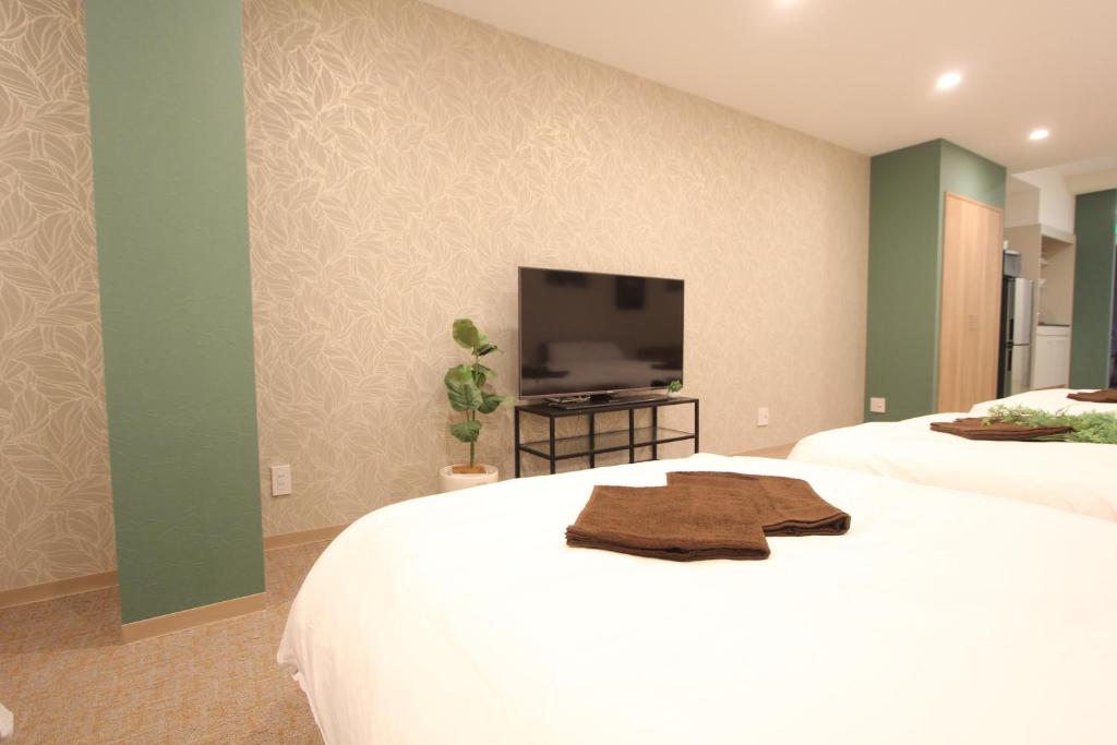 東京にあるLUANAHOTEL IN KOUENJIのベッドルーム1室(ベッド2台、薄型テレビ付)