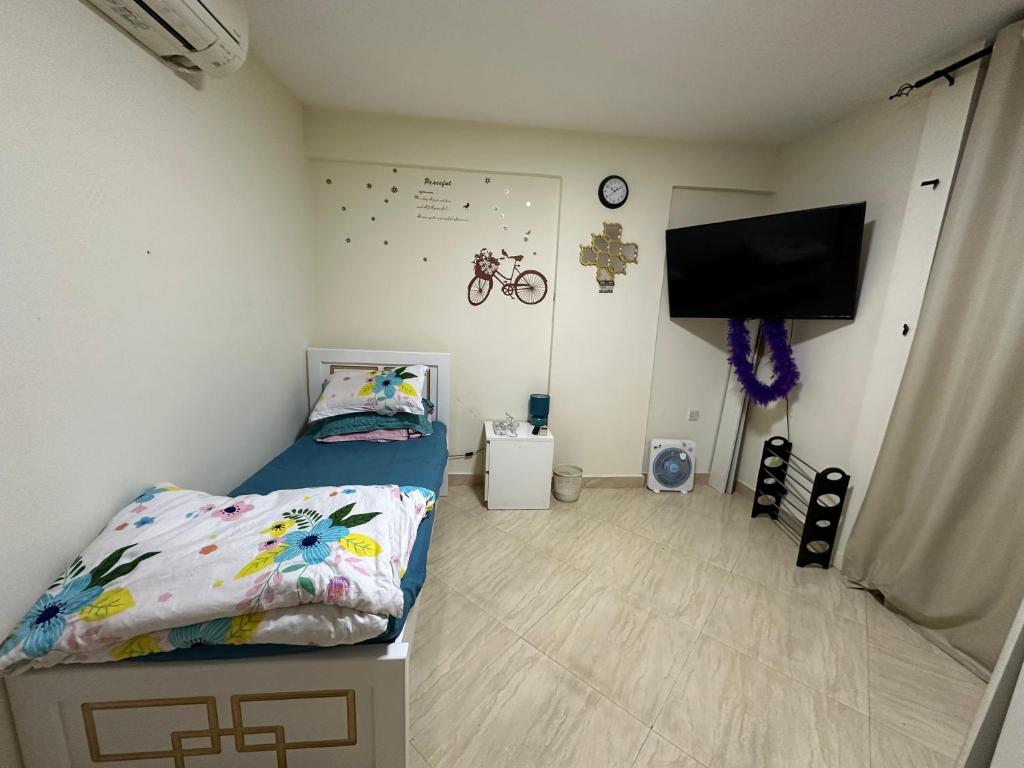 a small bedroom with a bed and a flat screen tv at Private Room Shared Apartment Flat31-R1 in Abu Dhabi