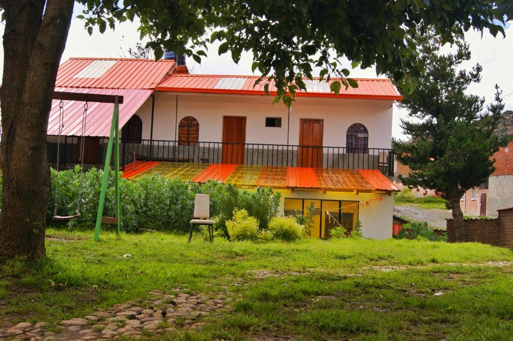 una casa con tetto rosso e un cortile di Hostal Ancohuma a Peñas