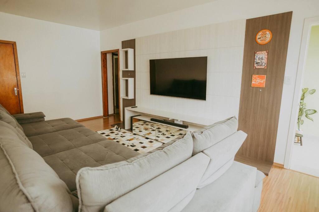 a living room with a couch and a flat screen tv at Ap completo melhor localização! Centro de Caxias. in Caxias do Sul