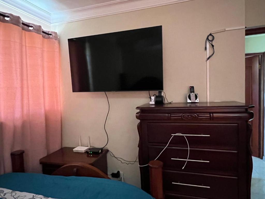 ein Schlafzimmer mit einem TV an der Wand und einer Kommode in der Unterkunft Cómodo y acogedor Amueblado in Santiago de los Caballeros