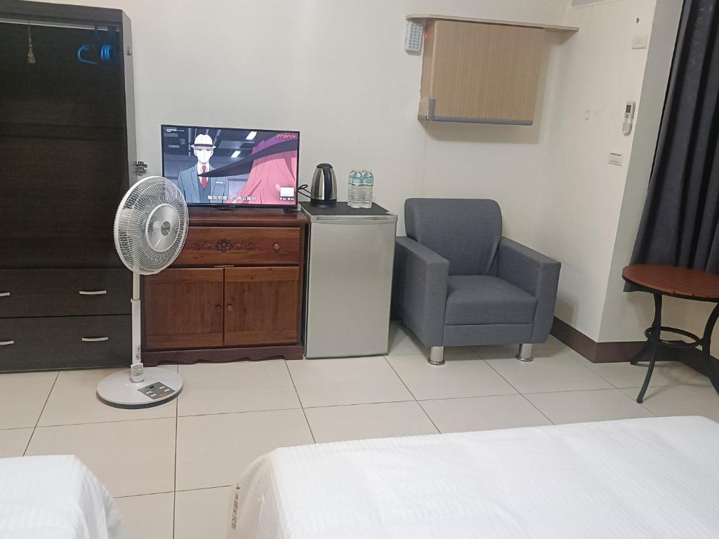 a bedroom with a tv and a chair and a fan at Yan Gui Lai B&B in Hengchun