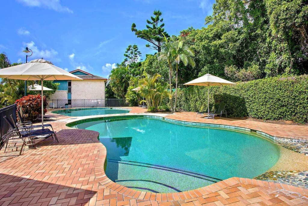 una piscina en un patio con sombrillas en Casa Tropicana - Couples Retreat - Aqua Luna, en Sapphire Beach
