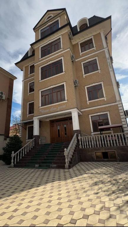 ein großes Gebäude mit einer Treppe davor in der Unterkunft CITY GARDEN HOTEL in Duschanbe