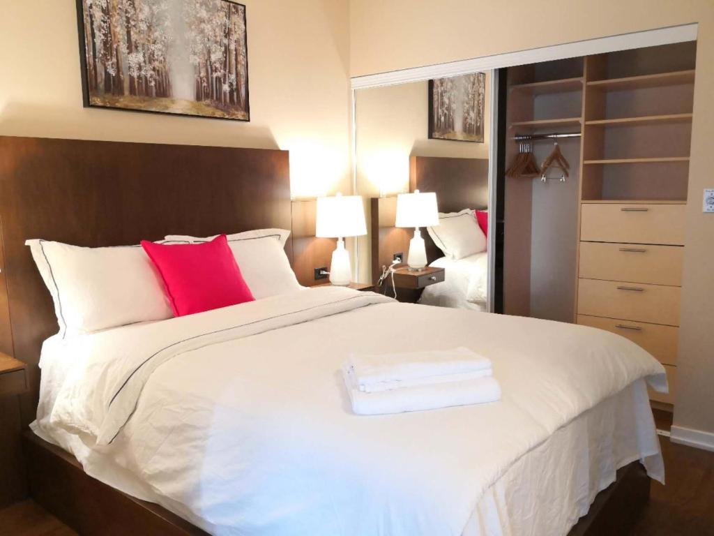 a bedroom with a large white bed with red pillows at Gorgeous Condo in Downtown Near CN Tower in Toronto