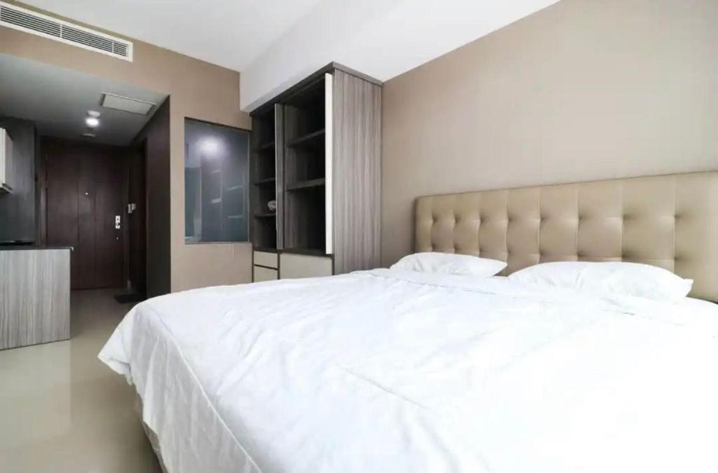 een slaapkamer met een groot wit bed met een groot hoofdeinde bij Collection O 93707 Rooms By U in Tangerang