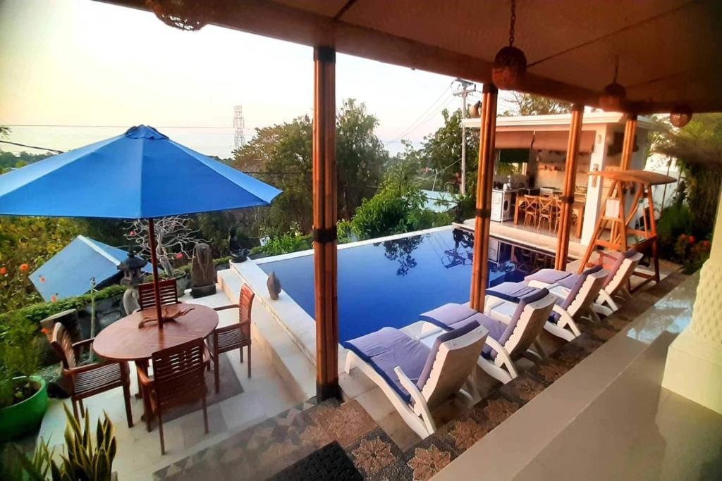 een zwembad met stoelen en een tafel en een parasol bij Tranquil Oasis Villa Near Lovina Beach in Temukus