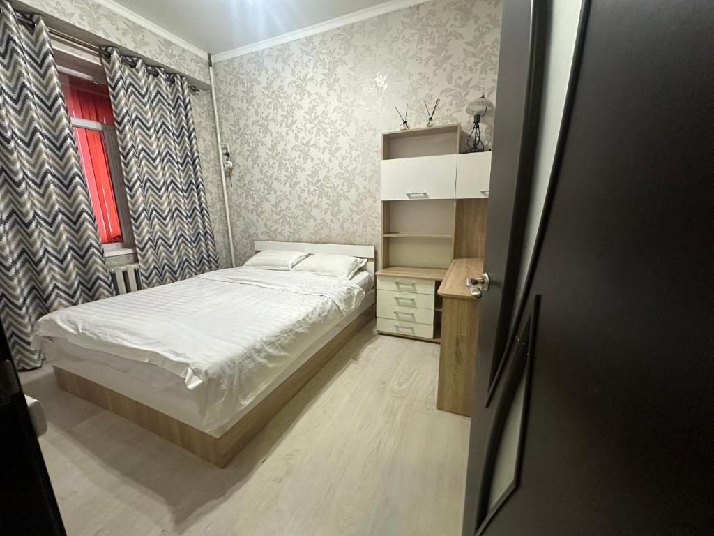 een kleine slaapkamer met een bed en een raam bij Center Cozy Apartment in Bisjkek
