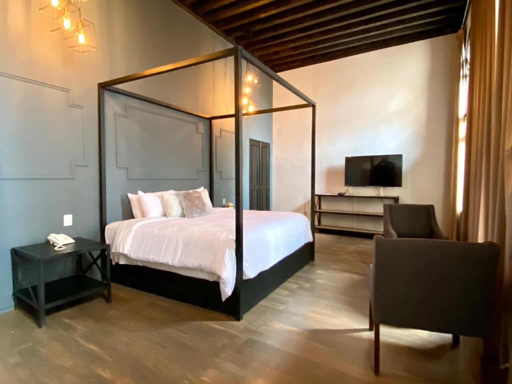 um quarto com uma cama de dossel e uma televisão em Hotel Plaza D Armas em Querétaro