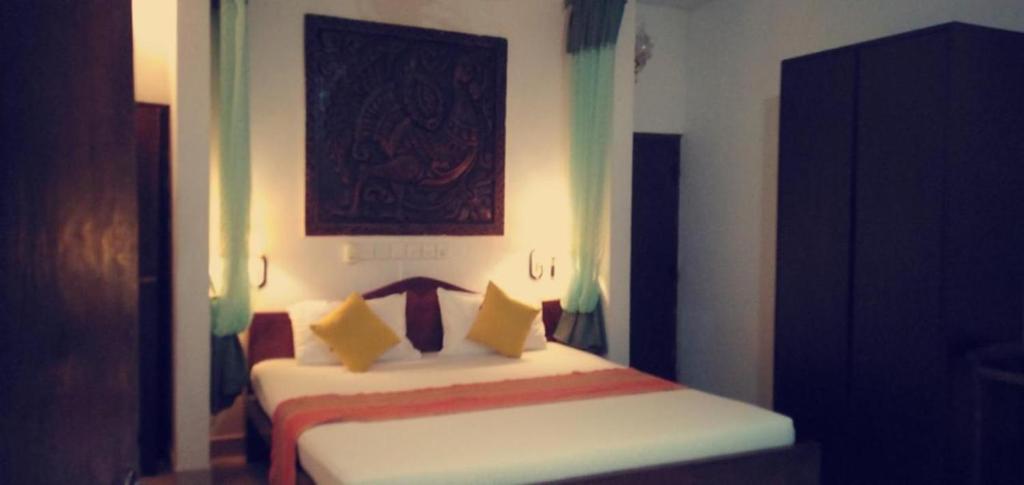 1 dormitorio con cama blanca y almohadas amarillas en Lihini Scandic Eco Village en Habarana