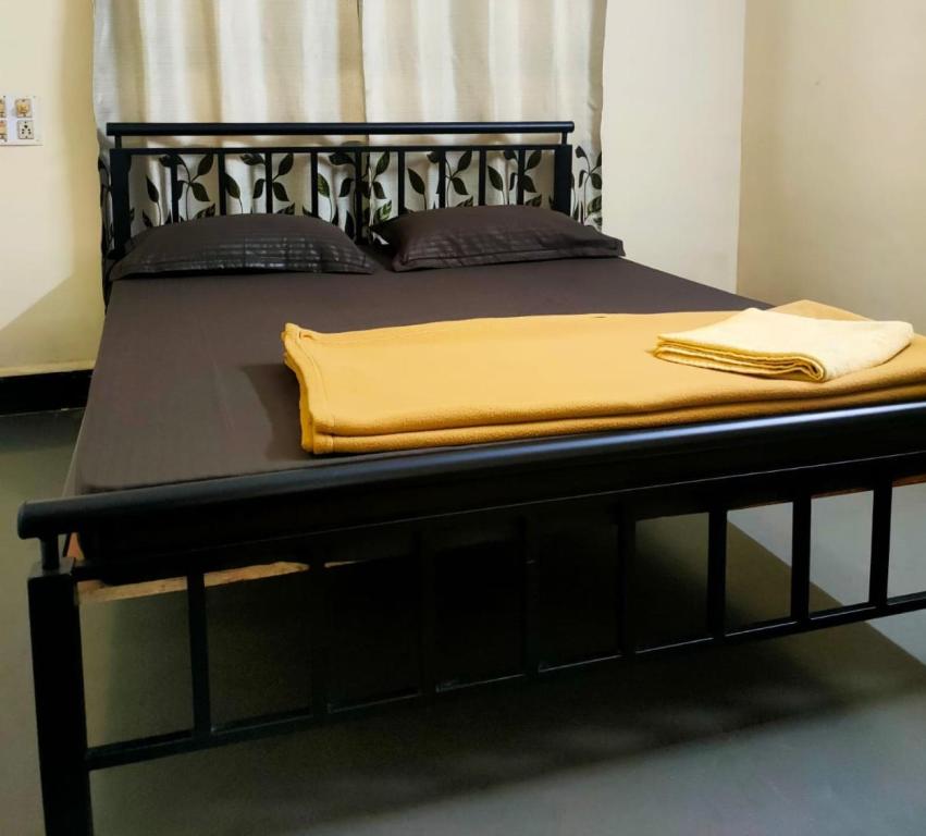 a black bed with a yellow blanket on it at Patil Homestay AC in Belgaum