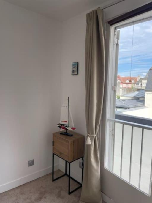Cette chambre dispose d'une fenêtre, d'une table et d'une fenêtre avec un rideau. dans l'établissement Studio hypercentre Villers-sur-Mer, à Villers-sur-Mer