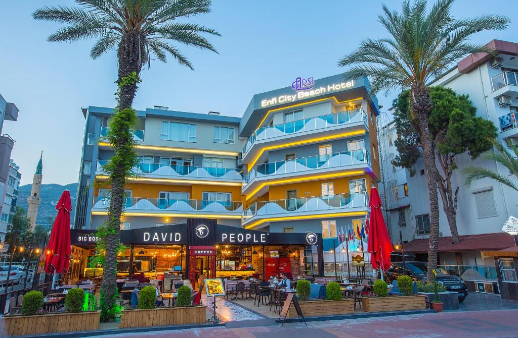 a hotel with palm trees in front of a building at Arsi Enfi City Beach Hotel in Alanya