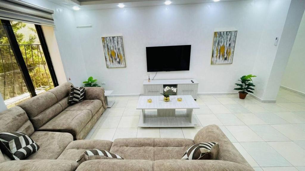 ein Wohnzimmer mit einem Sofa und einem TV in der Unterkunft Family Apt With New Ac in Amman