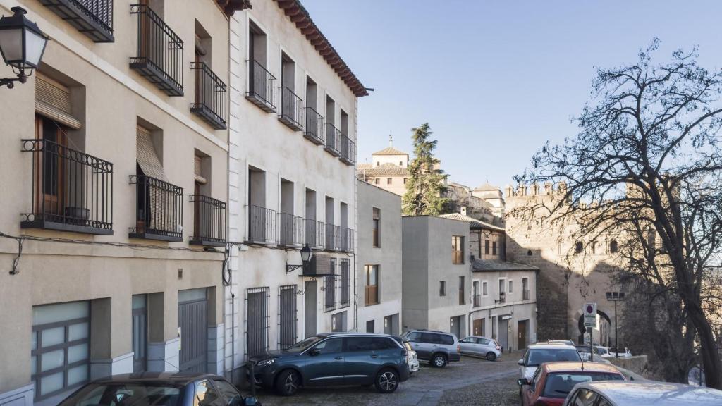un groupe de voitures garées dans une rue à côté des bâtiments dans l'établissement Apartamentos Zocosol by Toledo AP, à Tolède