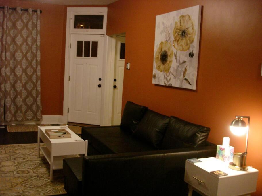 a living room with a black couch and an orange wall at St Louis House near Arch and Ballpark Village in Soulard