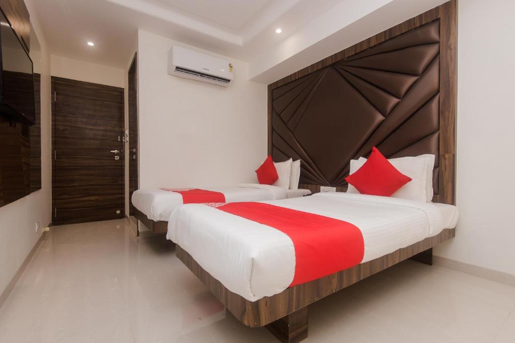 OYO Flagship Hotel Park Palace في مومباي: غرفة نوم بسريرين ومخدات حمراء وبيضاء