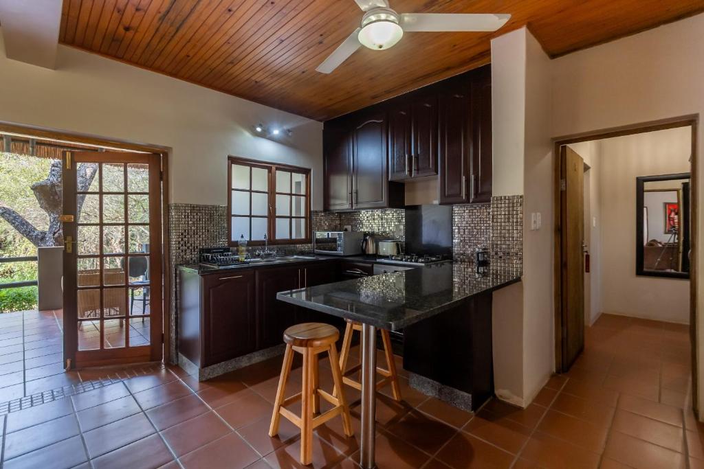 a kitchen with black cabinets and a bar with stools at Ndumu River Lodge in Jozini