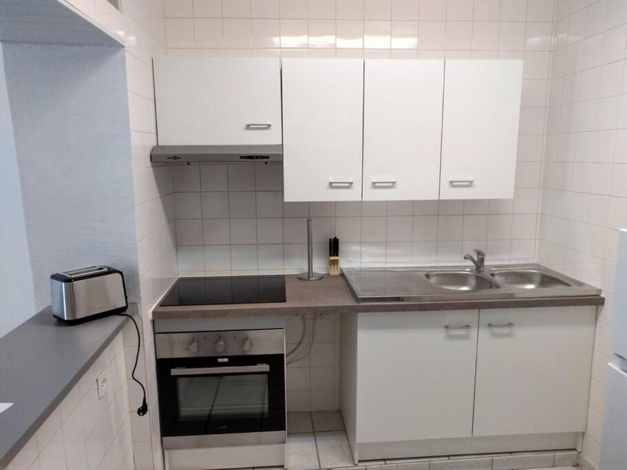 una pequeña cocina con armarios blancos y fregadero en Agréable maison 2 ch 5 mins Valenciennes et garage, en Anzin