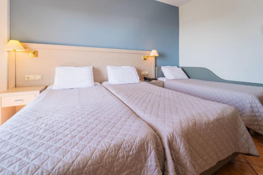 a bedroom with two beds with white comforters at Oceanis Hotel in Kavála