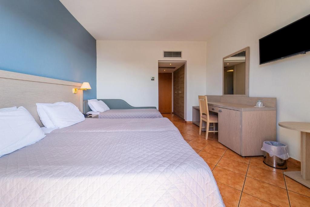 a hotel room with two beds and a desk at Oceanis Hotel in Kavála