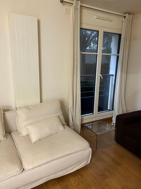 a white couch in a living room with a window at Cosy studio Puteaux in Puteaux
