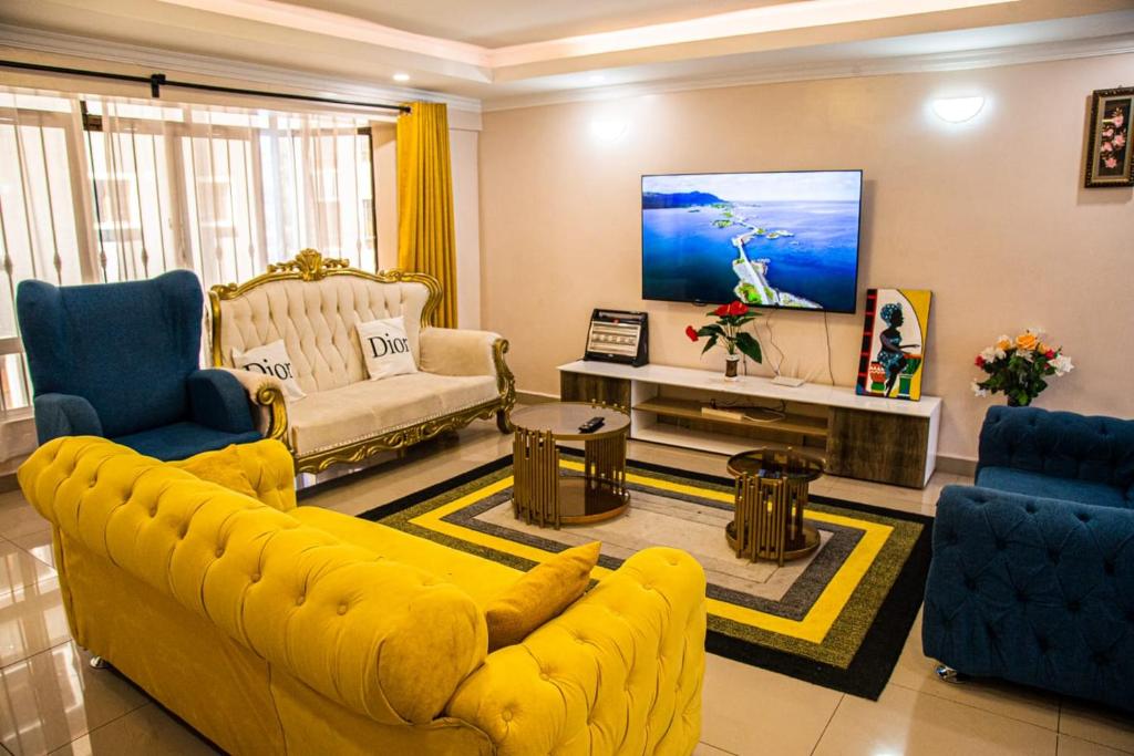 a living room with a yellow couch and blue chairs at Dylan Shawmutt Luxurious 3 Bedroom Apartment in Nakuru