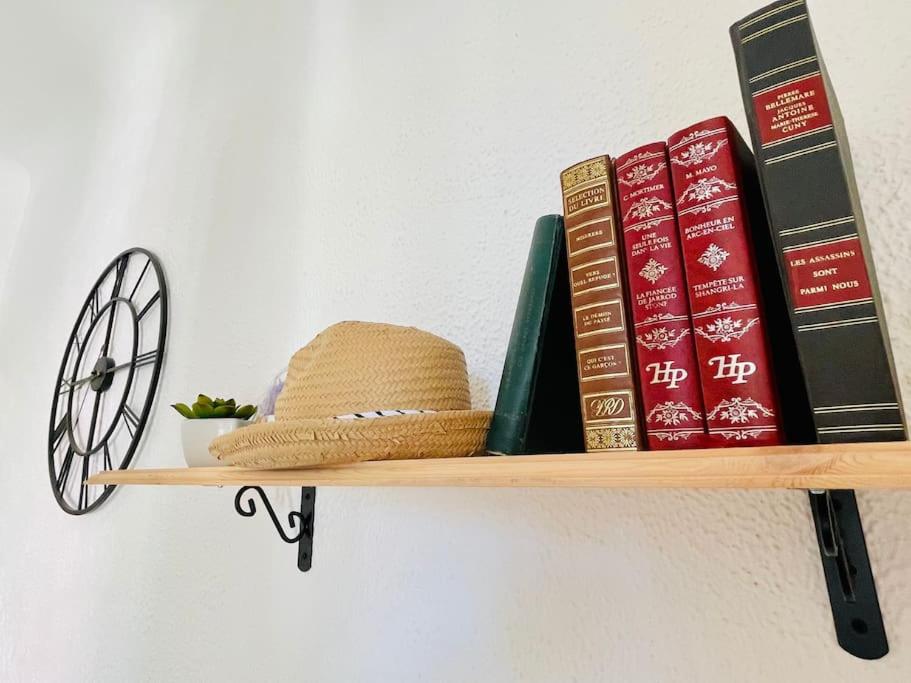 a shelf with books and a hat and a fan at Central studio AC & balcony in Nice