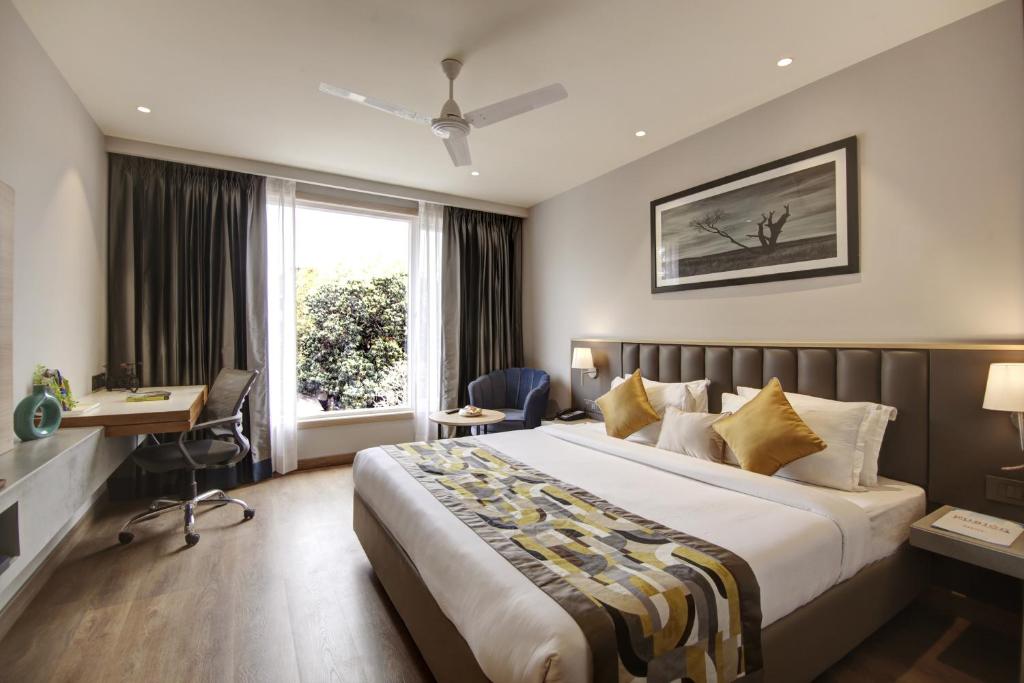 a hotel room with a bed and a desk and a window at East Park Inn in New Delhi