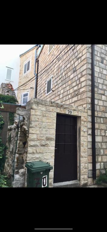a brick building with a door and a garbage can at Lili apartman in Vodice