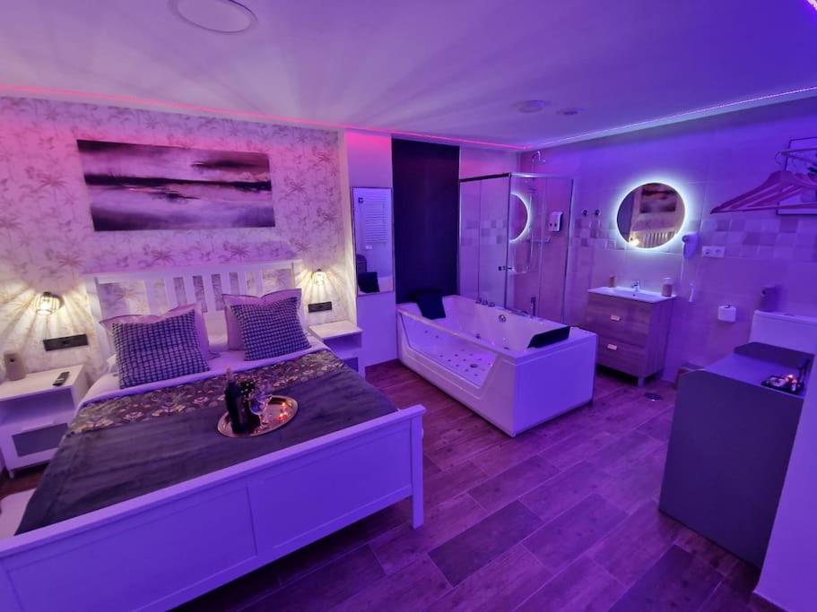 Dormitorio púrpura con cama grande y bañera en sensual sierra love en Prado del Rey