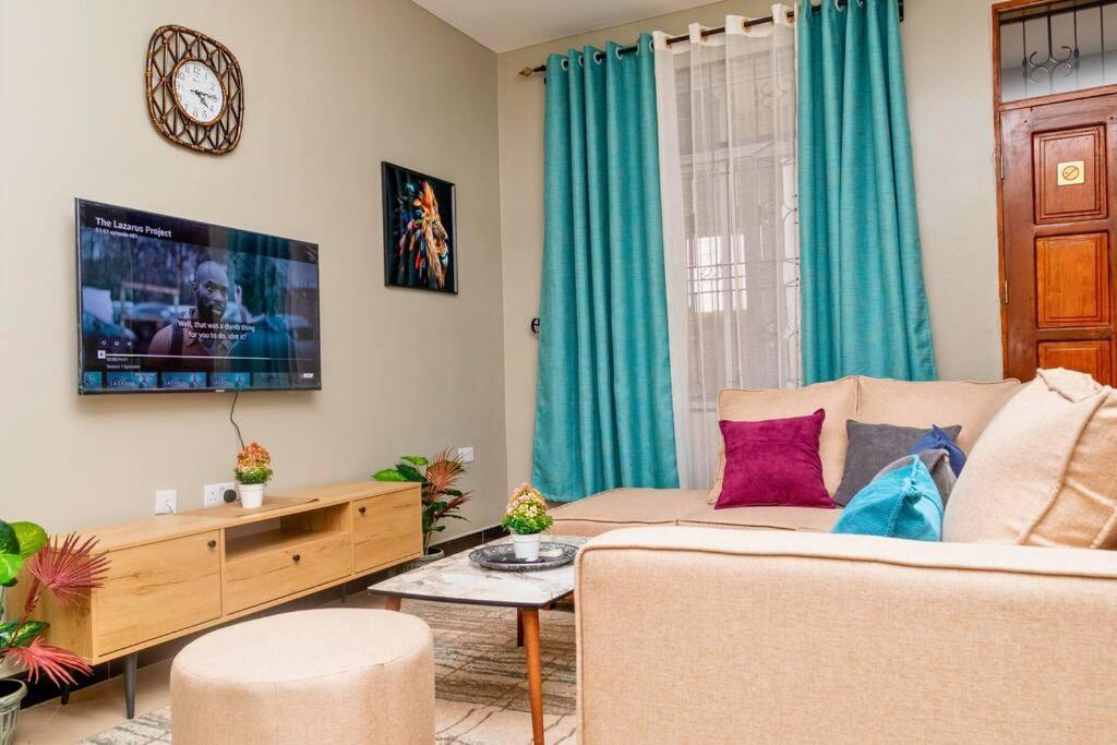 a living room with a couch and a tv at Family Friendly 2-BR Apartment Near Mlimani City in Dar es Salaam