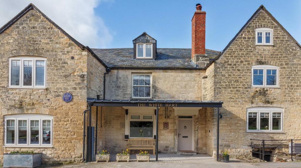 - un vieux bâtiment en pierre avec une façade en briques dans l'établissement A handsome large 9 bedroom 17th Century village house moments from The Cotswold Way offering modern luxury in a peaceful location, à Frocester