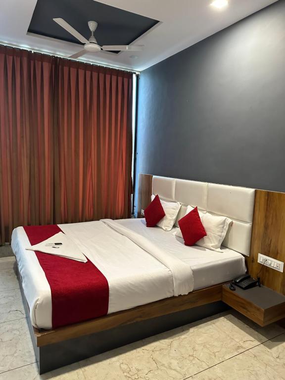 a bedroom with a large bed with red pillows at Hotel Dumas Near Airport in Surat