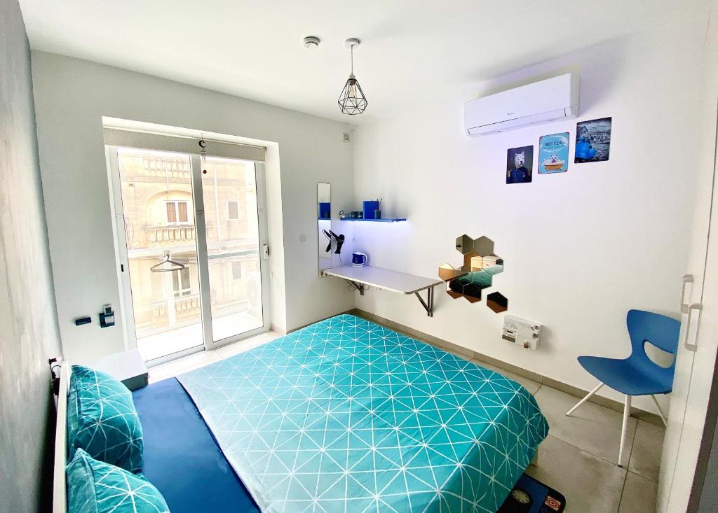 um quarto com uma cama azul e uma janela em Central- Private En-Suite with Balcony in shared residence em Tal-Pietà