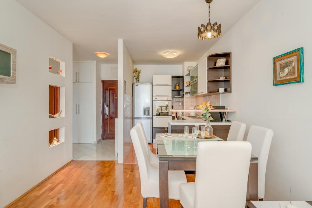 ein Esszimmer mit einem Tisch und weißen Stühlen in der Unterkunft Comfy & Urban apartment on Žnjan near beach in Split