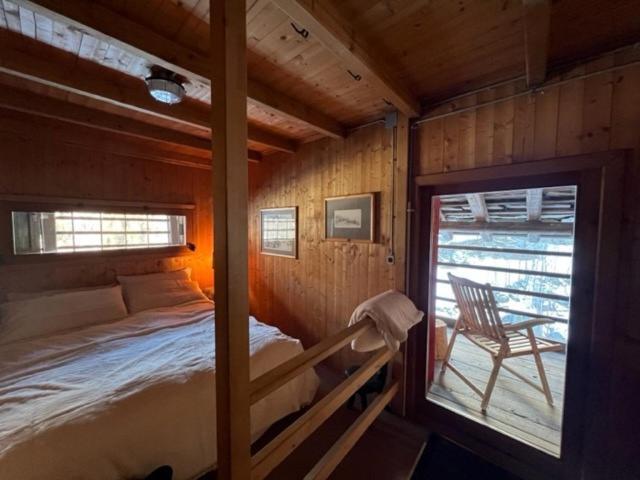 a bedroom with a bed and a chair in a cabin at Cozy 500 Years Old Walser Home in Alagna Valsesia