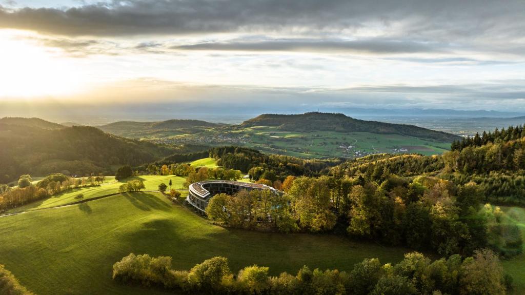 un bâtiment sur un champ verdoyant dans les montagnes dans l'établissement Luisenhöhe - Gesundheitsresort Schwarzwald, à Horben