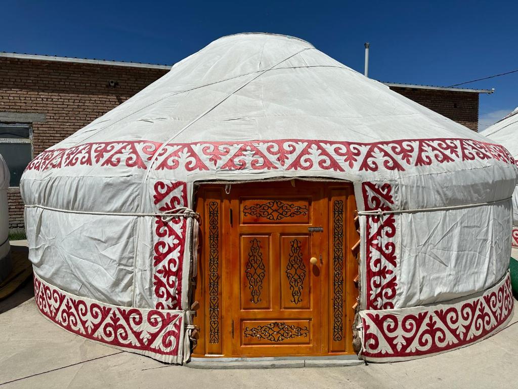 eine rot-weiße Jurte mit einer Holztür in der Unterkunft Traditional Yurts - Ulgii Guest House in Ölgii