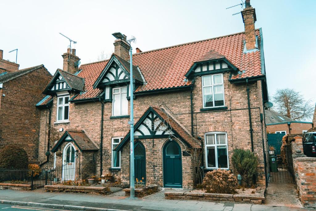 una antigua casa de ladrillo con techo rojo en Rose Cottage, en Brough