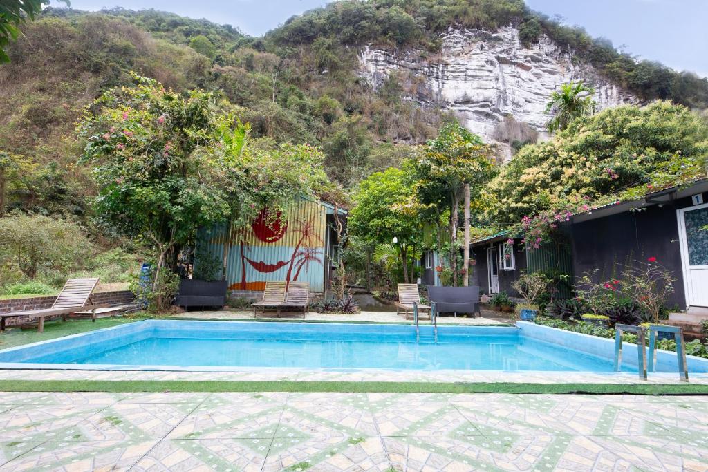 a house with a swimming pool in front of a mountain at Cat Ba Countryside Homestay in Cat Ba