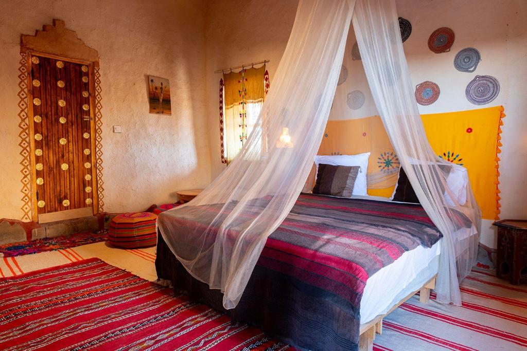 - une chambre avec un lit et une moustiquaire dans l'établissement kasbah hotel Luna, à Erfoud