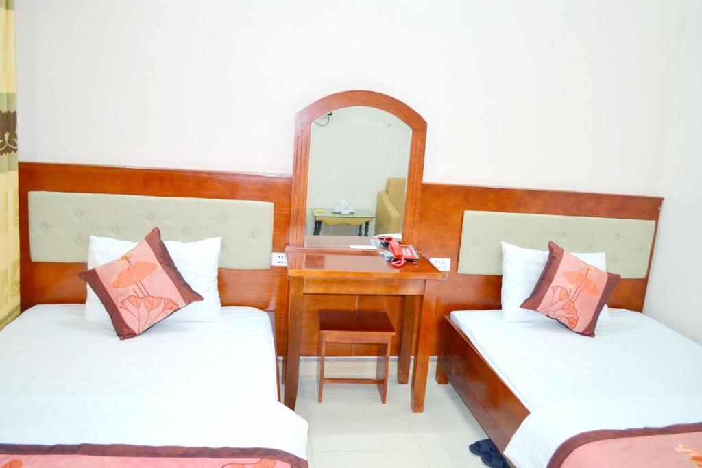 Cette chambre comprend deux lits, un bureau et un miroir. dans l'établissement Khách sạn Anh Đào, à Lạng Sơn