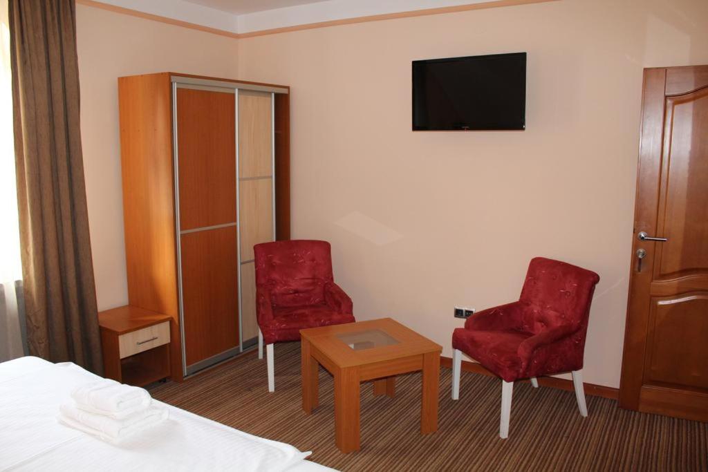 um quarto de hotel com duas cadeiras vermelhas e uma televisão em Motel Royal em Tuzla