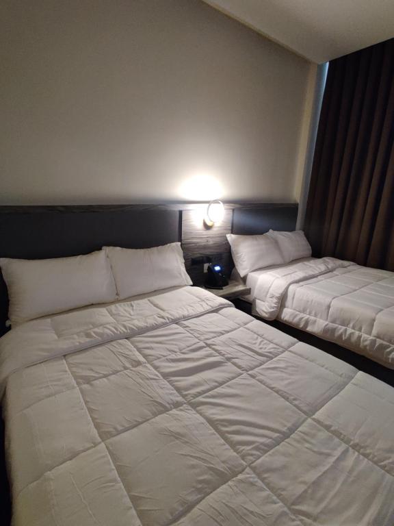 a bedroom with two beds and a lamp on the wall at Altori Park Hotel in General Santos