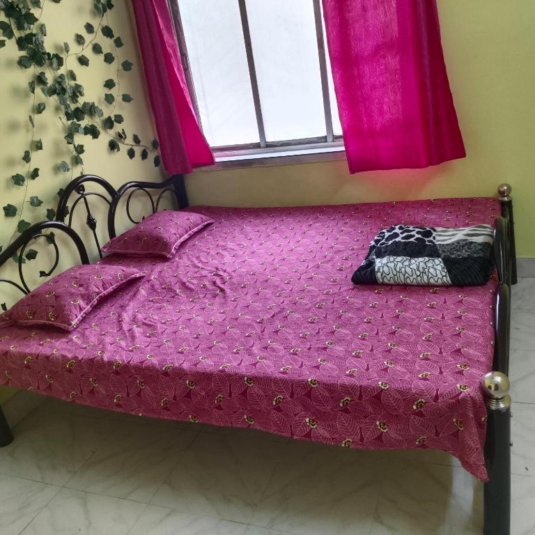 een bed in een kamer met roze lakens en een raam bij Lara stay 2bhk appartments in Calcutta