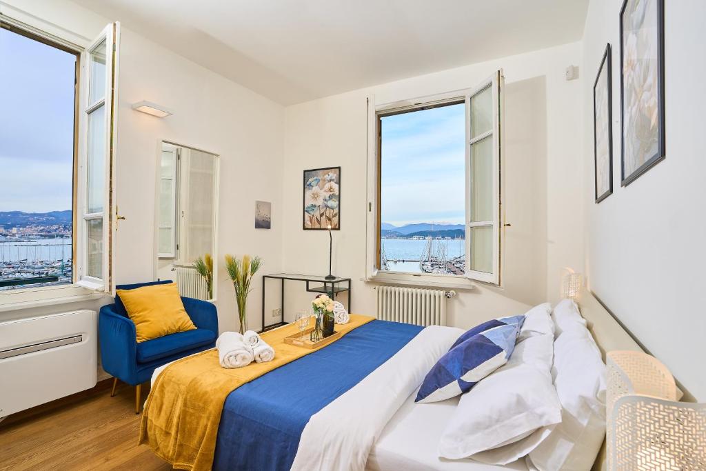um quarto com uma cama, uma cadeira azul e janelas em [Villa Privata] Vista Mare - in Portovenere em Fezzano