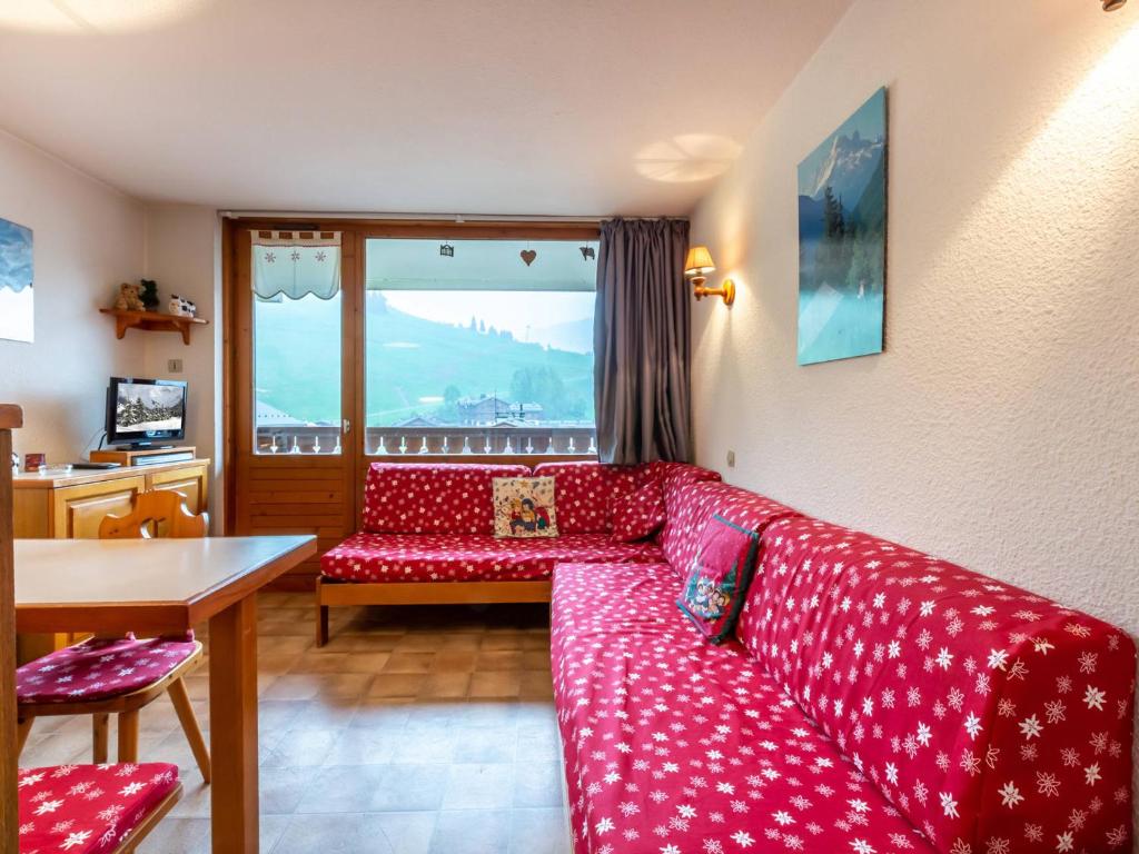 a living room with a red couch and a table at Appartement La Clusaz, 2 pièces, 5 personnes - FR-1-304-38 in La Clusaz