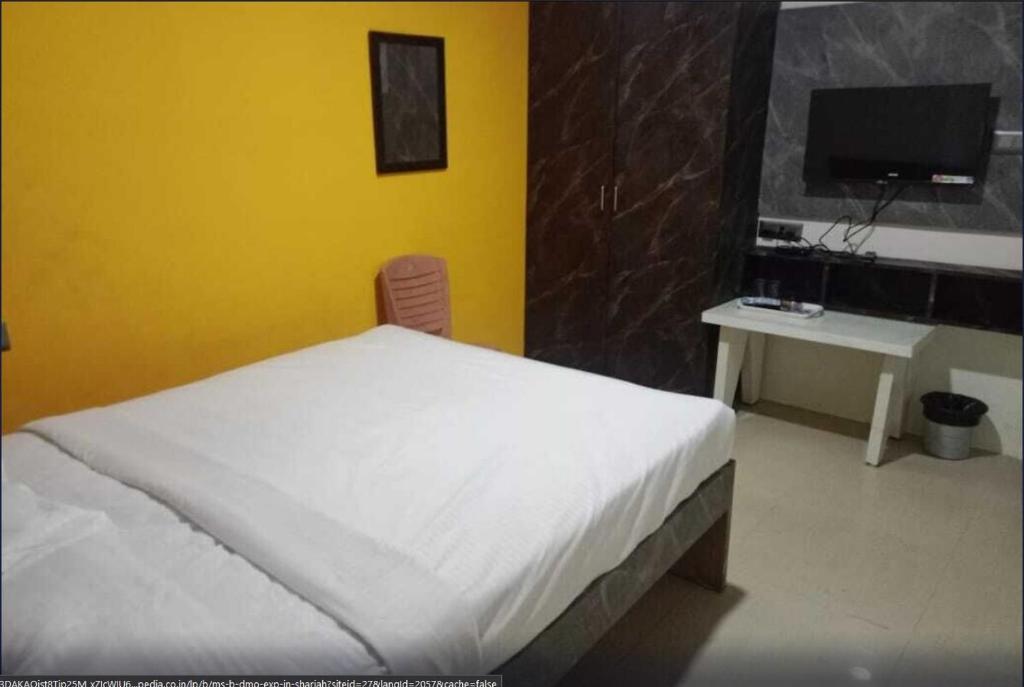 Navarang Residency Bar Top By Urban Express في بانغالور: غرفة نوم مع سرير ومكتب مع جهاز كمبيوتر