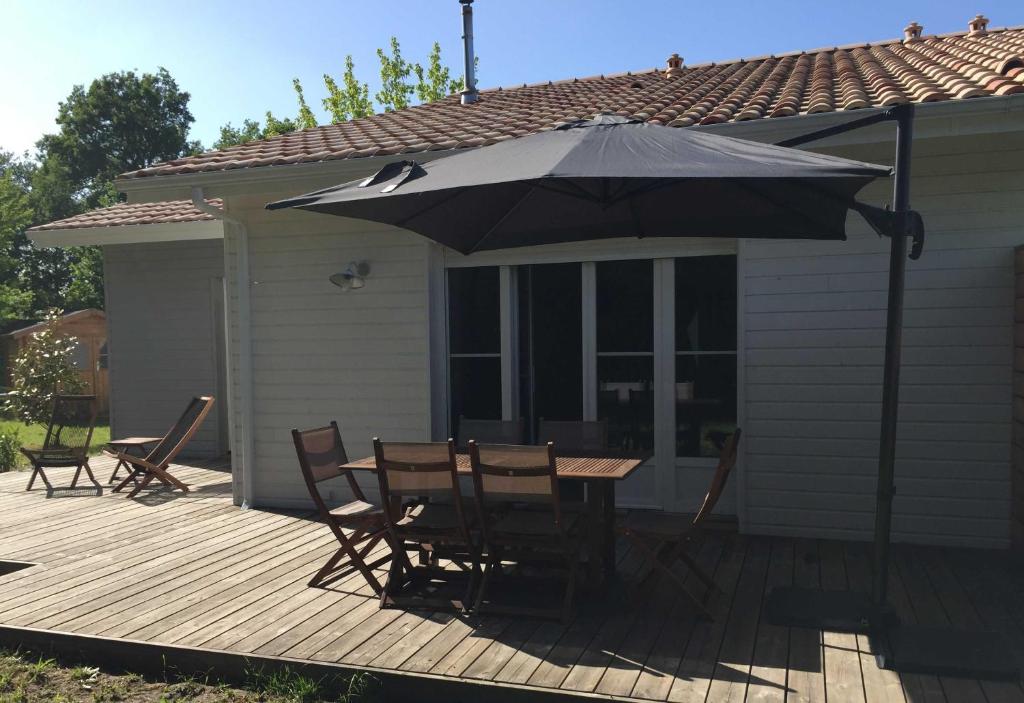 een tafel en stoelen op een terras met een paraplu bij Very beautiful house - Bassin d'Arcachon in Arès